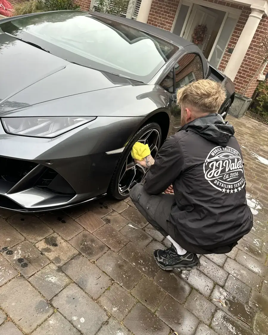 JJ Valets hand-drying the wheel of a grey Lamborghini Huracan on a customer's driveway, Chichester