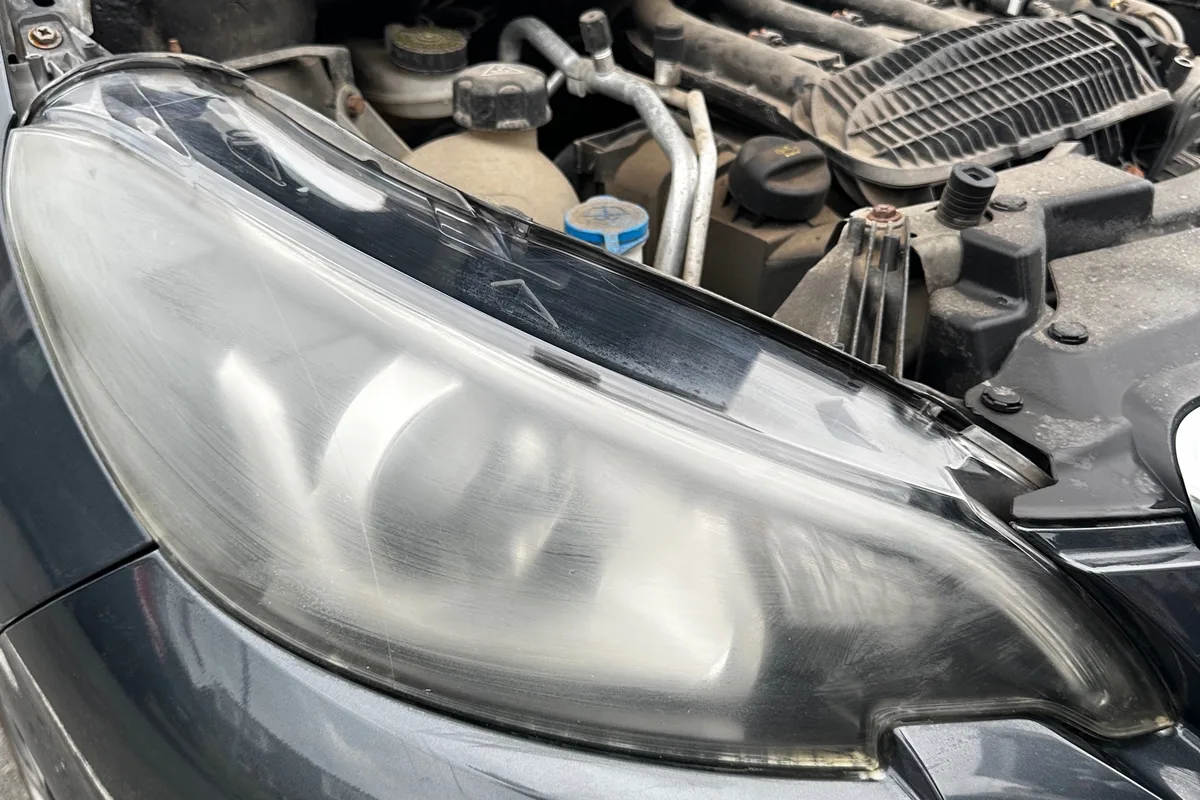 Before: Headlight restoration by JJ Valets on a grey Peugeot: cloudy, scratched headlight before and crystal clear after, Bognor Regis