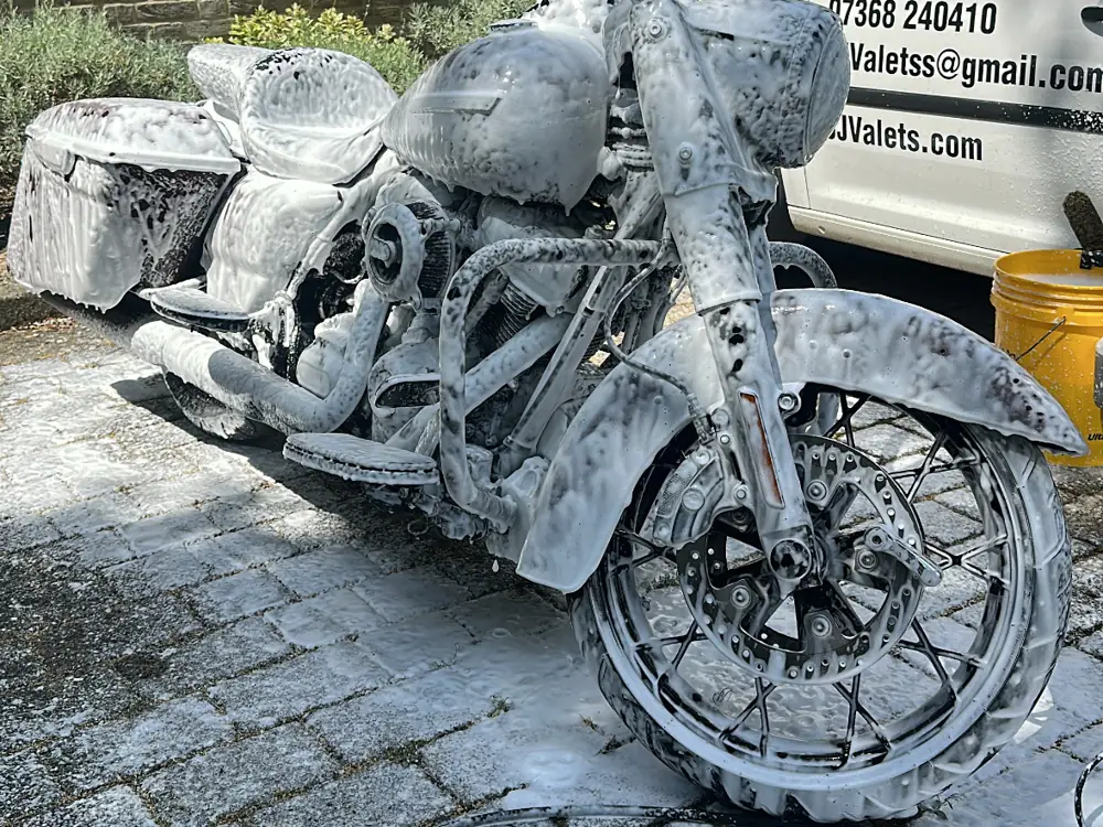 Cruiser motorbike covered in snow foam during a motorbike detail by JJ Valets, with the JJ Valets van behind, Chichester
