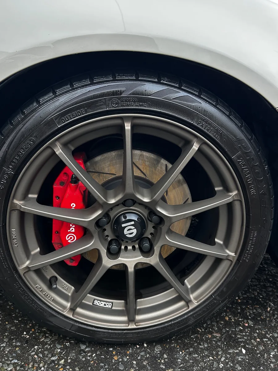 After: Wheel and tyre clean by JJ Valets on a white car with Sparco wheels and red Brembo calipers: grimy wheel before and clean wheel with dressed tyre after